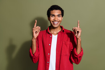 Photo of excited funky man dressed red shirt pointing two fingers up empty space isolated green...