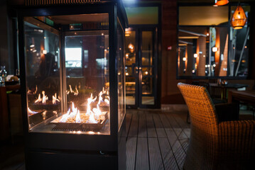 A luxurious lounge in Engelberg with a modern glass fireplace, wicker chairs, and elegant lighting,...