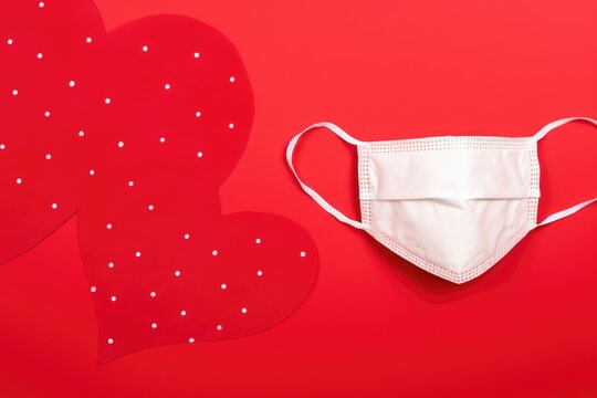 Heart-Shaped Face Mask on Red Background. Protective mask alongside heart decor.