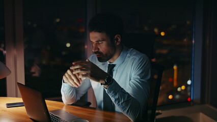 Worried manager sitting night workplace looking laptop close up. Worker tired 