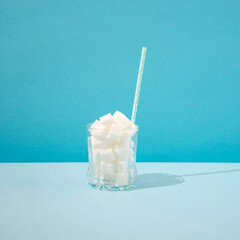 Glass Filled Sugar Cubes With paper straw  on blue background.