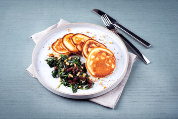 Traditional American pancakes with spinach, pine-nuts and raisins served as close-up on a Nordic...