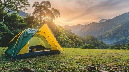 Small Yellow and Green Camping Tent Picnic on green lawn behind mountain sunrise morning sky background, Recreation and outdoor travel concept.