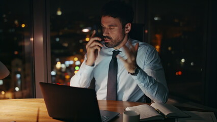 Stressed businessman yelling smartphone sitting office desk late evening closeup