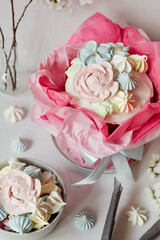 Festive Easter table in delicate colors: cake decorated with meringue, icing, flowers. Sweets in the form of flowers, apple blossoms, Easter eggs.