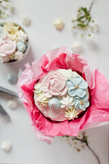 Festive Easter table in delicate colors: cake decorated with meringue, icing, flowers. Sweets in the form of flowers, apple blossoms, Easter eggs.