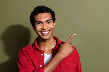 Photo of positive good mood guy wear red shirt showing finger empty space isolated khaki color...