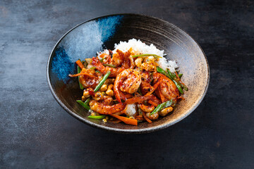 Traditional Thai fried king prawns with vegetable, cashew nuts and rice served as close-up in a design bowl with text space