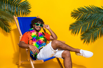 Portrait of cool guy wear hawaii print shirt touching glasses lay on chair on vacation isolated on...