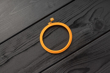 An orange silicone circular bracelet on a dark wooden background