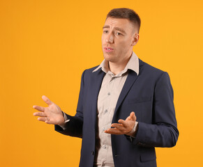 A man in a blue suit gesturing with his hands as if in the middle of a conversation or argument,...