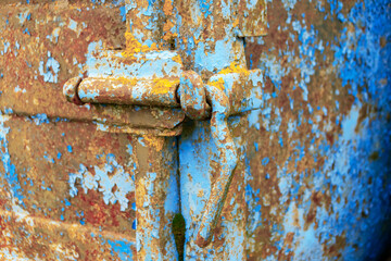 Rusty metal hinge with chipped blue paint.