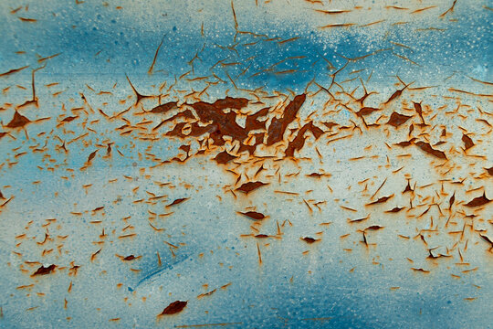 Chipped and cracked blue paint on rusted metal surface