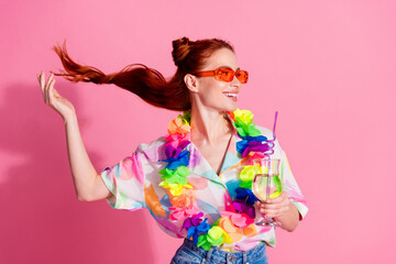Portrait of young girlfriend in glamour shirt touch red hair knot with hawaii necklace and drink mojito isolated on pink color background
