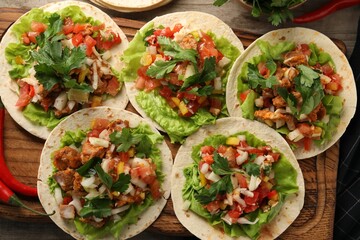 Delicious tacos with vegetables and meat on wooden table, flat lay
