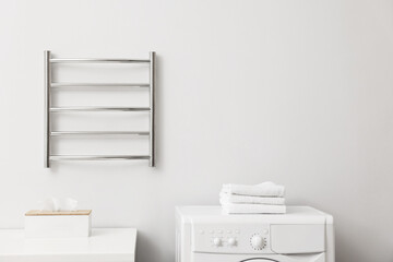 Heated towel rail on white wall in bathroom, space for text