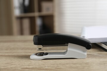 One stapler on wooden table indoors, closeup