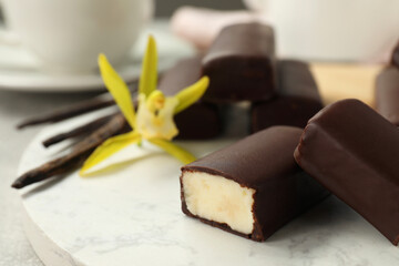 Glazed curd cheese bars, vanilla pods and flower on board, closeup