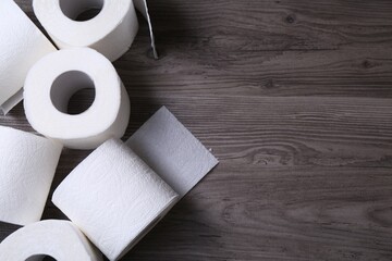 Soft toilet paper rolls on wooden table, flat lay. Space for text