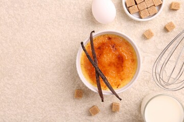 Delicious creme brulee in bowl and ingredients on light textured table, flat lay. Space for text