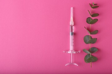 Cosmetology. Medical syringe and eucalyptus branch on pink background, flat lay. Space for text