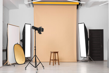 Beige photo background, stool and professional lighting equipment in studio