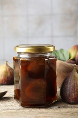 Jar of tasty sweet jam and fresh figs on wooden table