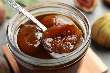 Jar of tasty sweet fig jam on table, closeup