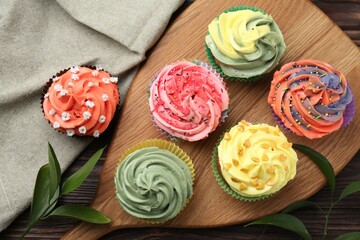 Delicious cupcake with bright cream on wooden table, flat lay