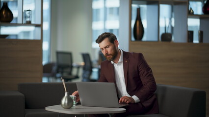 Worried businessman drinking espresso looking computer office. Man feeling tired