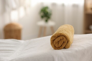 Fototapeta na wymiar Rolled towel on massage table in spa center, closeup. Space for text