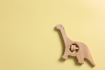 Baby accessory. Wooden rattle on yellow background, top view. Space for text