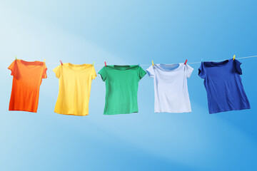 Colorful t-shirts drying on washing line against blue sky