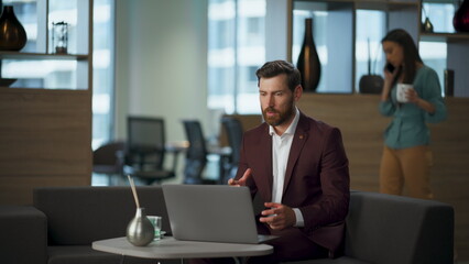 Confident ceo conducting video meeting with partners sitting office in suit