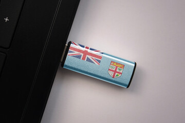 usb flash drive in notebook computer with the national flag of Fiji on gray background.