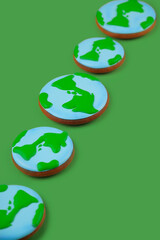 Earth Day concept. Сookies in shape of Earth on green backdrop.