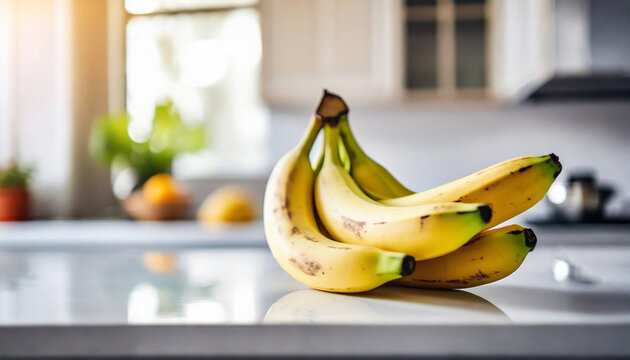 Bananas on white tabletop, kitchen blurred background. Symbolic stock photo of freshness and health