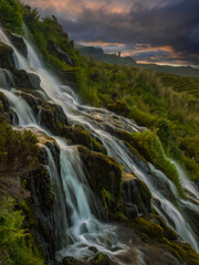 Otherworldly scenery with a beautiful cascading waterfall and Old Man of Storr