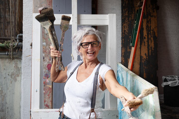 smiling laughing happy older mature woman portrait, proud artist, in her fifties with grey hair and...