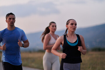 A diverse group of runners trains together at sunset.