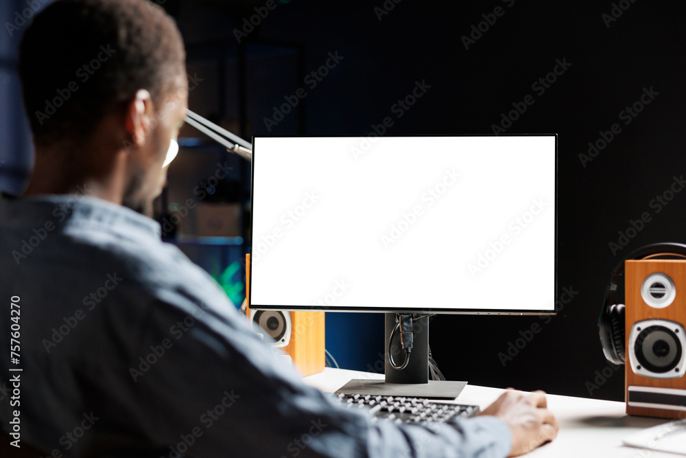 Poster man examines white display on workstation while telecommuting and uses empty screen on monitor. male