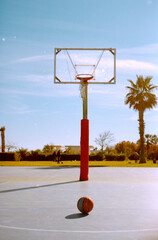 red basket in an outdoor basketball court with trees behind 