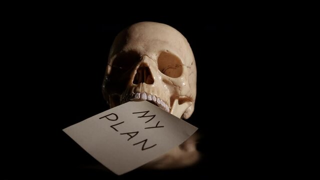 Plan failure in human life. A human skull with unpleasant plans for future in its mouth on black background.