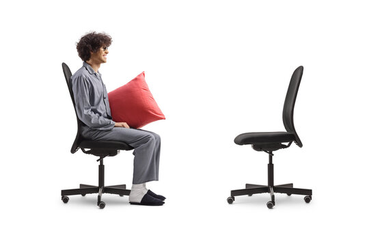Profile shot of a man in pajamas sitting and looking at an empty office chair