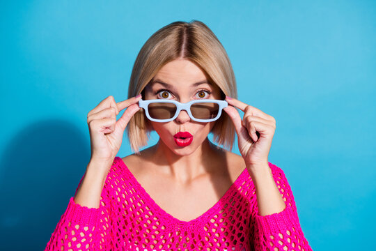 Photo portrait of attractive young woman touch 3d glasses impressed dressed stylish pink knitwear clothes isolated on blue color background