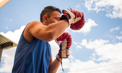 Latin young boxer man training with red boxing gloves in latin outdoors gym