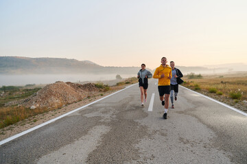 Obraz premium A group of friends, athletes, and joggers embrace the early morning hours as they run through the misty dawn, energized by the rising sun and surrounded by the tranquil beauty of nature