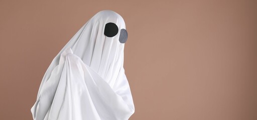 Creepy ghost. Person covered with white sheet on dark beige background, space for text