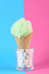 Sweet cotton candy in waffle cone on color background