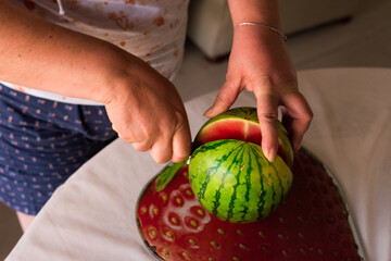 Woman cutting watermelon at home